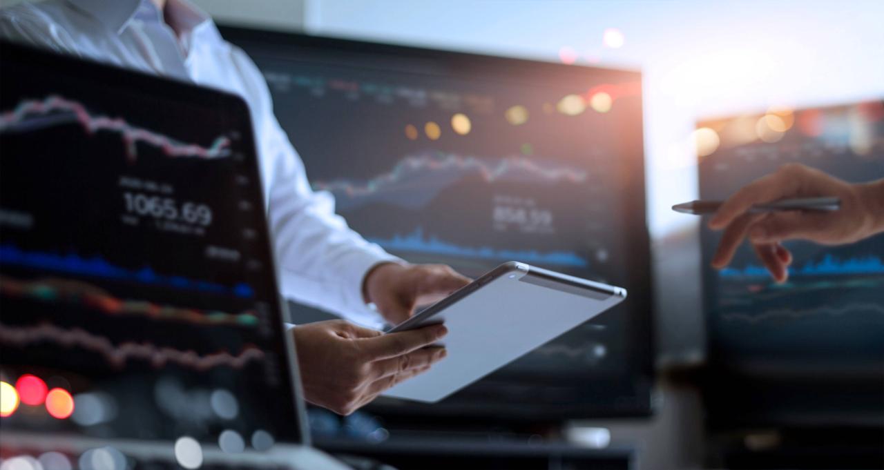 Business team working together. Businessman using tablet for analyzing data stock market in monitoring room with team pointing on the data presented in the chart on screen, forex trading graph, stock exchange trading online, financial investment concept. All on laptop screen are design up.