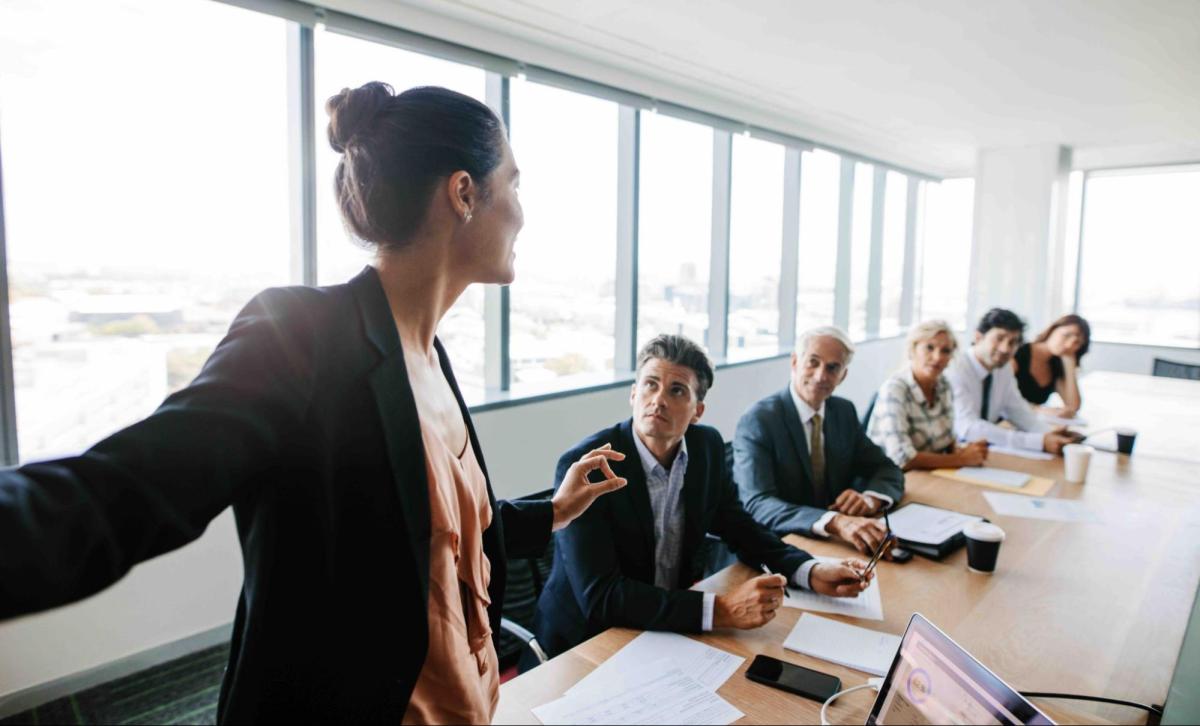 photo of a female executive presenting to the board in a conference room