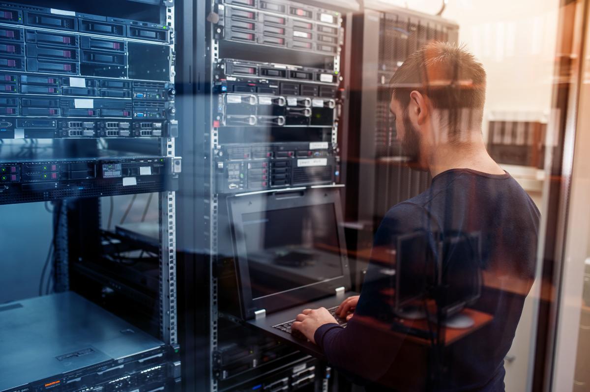 Photo of IT professional typing on a laptop inside a server room