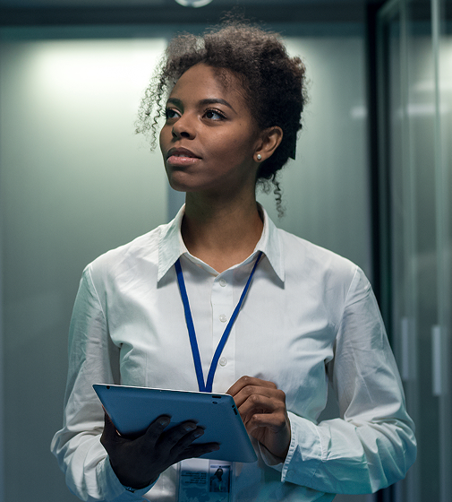 Empleado con una tableta en la mano inspeccionando bastidores de servidores dentro de un centro de datos