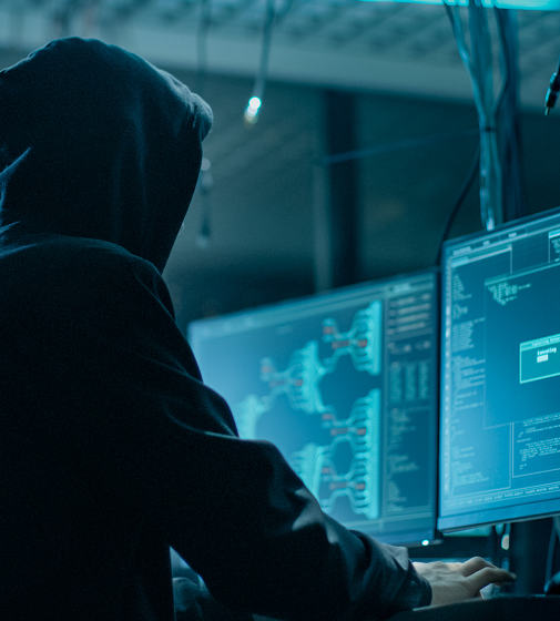 Hacker sentado frente a un escritorio codificando activamente con las manos en el teclado